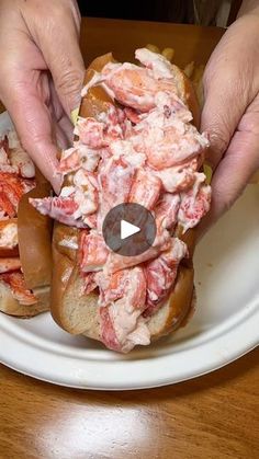 two hands grabbing a lobster sandwich from a white plate