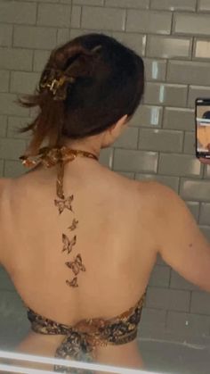 the back of a woman's body with butterflies on her upper and lower back