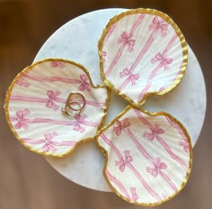 three pink and white plates with rings on them