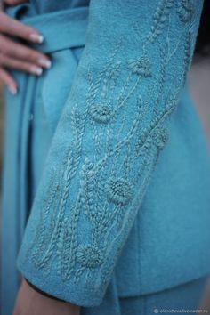 a woman's blue dress with flowers and leaves on the sleeves is shown in close up