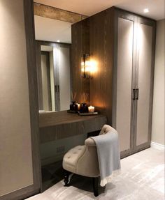 a chair sitting in front of a mirror next to a counter with candles on it