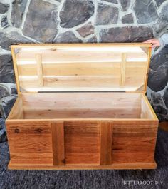 an empty wooden box sitting on top of a carpeted floor next to a stone wall