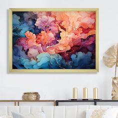 an abstract painting hangs above a couch in a living room with white walls and gold accents