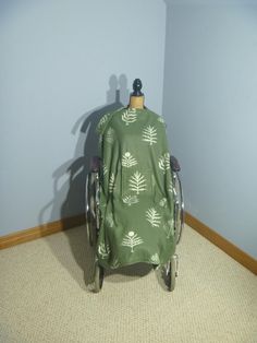 a chair covered in a green leafy blanket sitting on the floor next to a blue wall