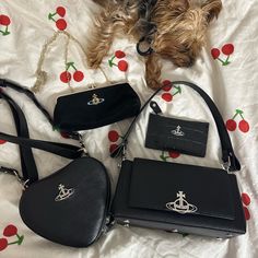 a dog laying on top of a bed next to two purses and a handbag