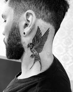 a man with a bird tattoo on his neck and behind the ear is a black - and - white photo