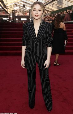 a woman in a pinstripe suit standing on the red carpet at an event