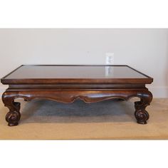 a wooden coffee table with glass top on carpeted floor