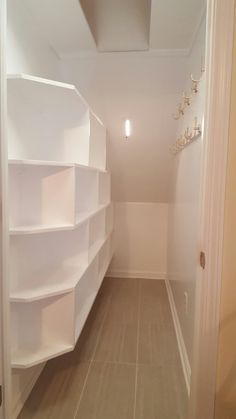 an empty white closet with shelves on the wall