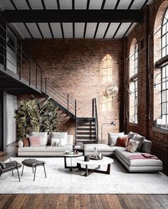 a living room filled with lots of furniture next to a stair case on the wall