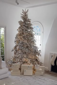 a white christmas tree with presents in front of it