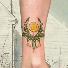 a woman's foot with a flower tattoo on her left side and yellow flowers on the other side