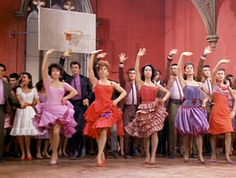 a group of people standing around each other in front of a basketball hoop with their hands up