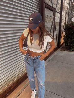 yankees game outfit, yankees hat, jeans, mom jeans, mom jeans with rips, white crop top, adidas shoes, outfit inspo, outfit ideas, outfit aethetics, outfit ideas layout Casual Game Day Outfits, Rays Game Outfit, Blue Baseball Hat Outfit, Nationals Game Outfit, Outfit Ideas Baseball Game, Cute Dodgers Game Outfit, Yankees Baseball Game Outfit, Mariners Game Outfit Woman, Baseball Fan Outfit