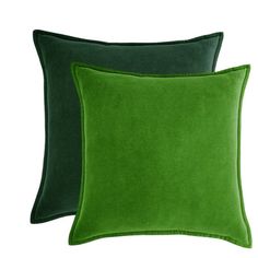 two green velvet pillows with contrasting colors on the front and back, one in dark green