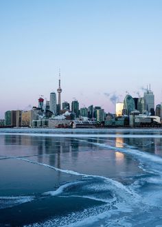 the city skyline is reflected in the icy water