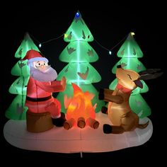 an inflatable christmas scene with santa and reindeer around a campfire at night