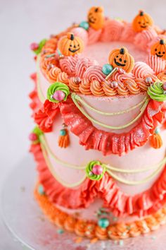 a three layer cake decorated with pumpkins and ruffles on a glass plate