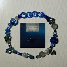 a blue beaded bracelet with glass beads and silver letters on it, in front of a white background