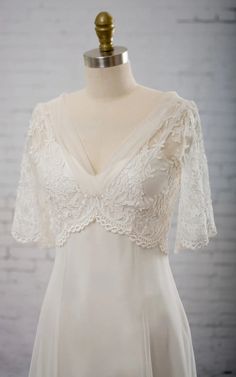 a white wedding dress on a mannequin with a brick wall in the background