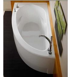 an oval shaped bathtub in the corner of a room with pictures on the wall