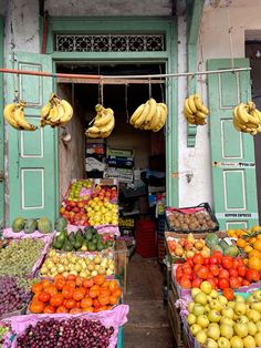 an open market with lots of fruits and vegetables hanging from the ceiling in front of it