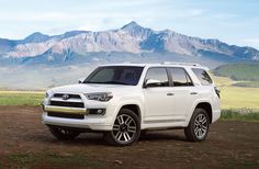 a white toyota 4runner parked in front of some mountains with grass and dirt on the ground