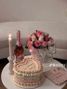 a table topped with a heart shaped cake next to a bottle of wine and flowers