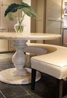 a white table and chair with flowers in a vase on it's pedestals