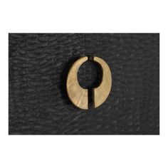 a wooden circle hanging from the side of a black leather wall with a metal ring on it