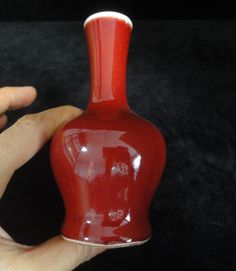 a person holding a red vase in their hand