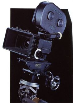 an old movie camera on a tripod in front of a black background with the lens up