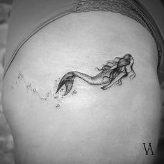 a woman's stomach with a mermaid tattoo on her belly and water droplets coming out of it