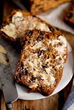 two slices of bread on a plate with butter and raisins next to it