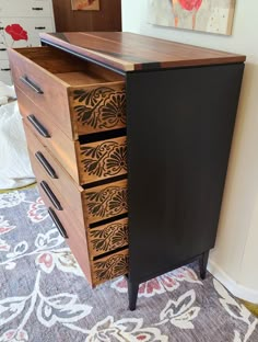 a black and brown dresser with drawers on it's sides in a room next to a painting