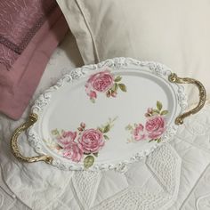 a white tray with pink roses on it sitting on a bed next to two pillows