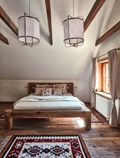 a large bed sitting in the middle of a bedroom next to two windows with wooden beams