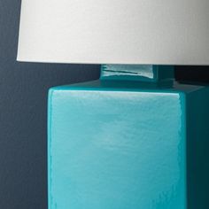 a blue table lamp with a white shade on the top and bottom part of it