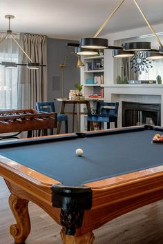 a pool table in the middle of a living room with chairs and tables around it