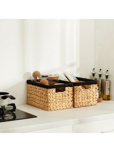 two wicker baskets sitting on top of a white counter next to a frying pan