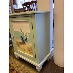 a cabinet that has a painting on the front and side of it with a beach scene