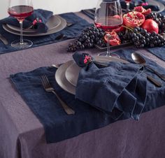 the table is set with blue linens and silverware, including two glasses of red wine