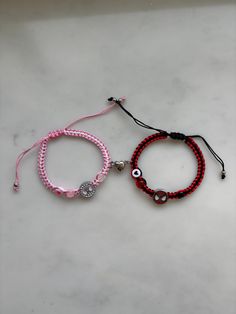 two bracelets with evil eyes on them sitting on a white table next to each other