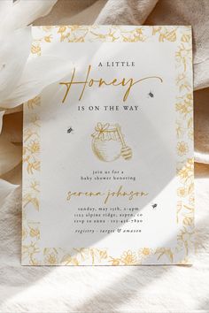 a little honey is on the way baby shower card with white flowers and gold foil