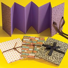 an origami box is open and sitting on a yellow surface with two pieces of paper