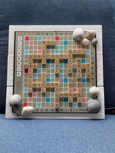 a scrabble board sitting on top of a blue couch with sea shells around it