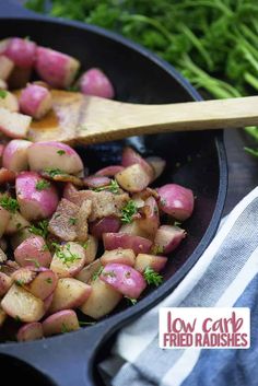 a skillet filled with potatoes and parsley on top of a striped towel next to fresh greens