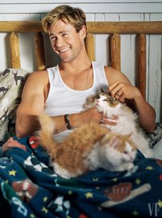 a man sitting in bed with two cats