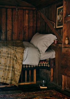 a bed in a room with wooden walls and a rug on the floor next to it