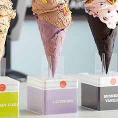 three ice cream cones with sprinkles and toppings on display in front of the camera